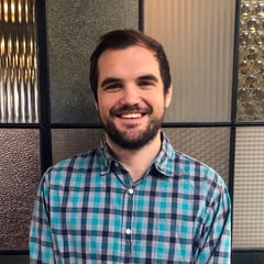 A headshot of Dillon Friday. He's smiling and wearing a checkered button down.